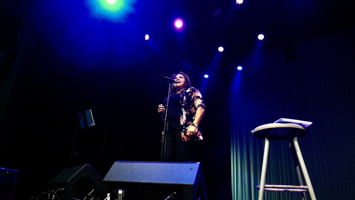 Une femme chante dans un micro sur une scène. 