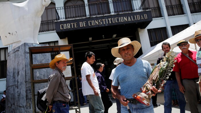 Un hombre sostiene en sus manos una estatua de la Virgen María frente al edificio del Tribunal Constitucional.