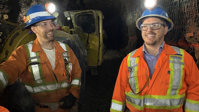 Deux mineurs, tout sourires, dans la galerie d'une mine.