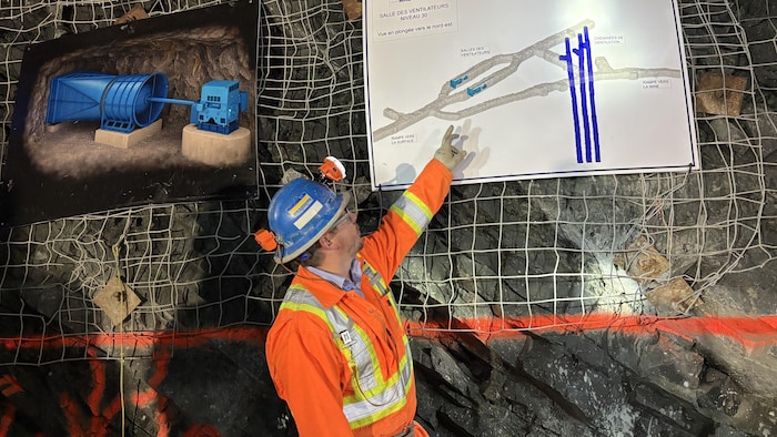 Un mineur pointe une carte indiquant les ventilateurs d'une mine.