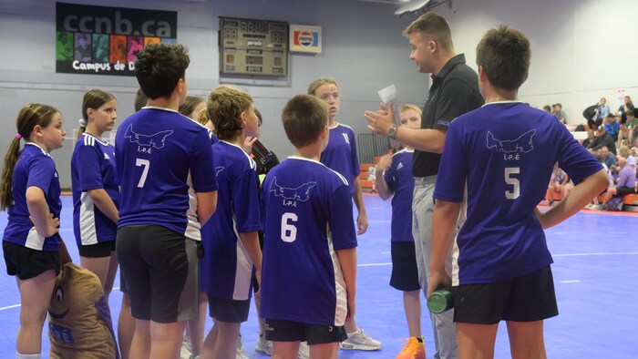 Les joueurs de mini-handball reçoivent des consignes de leur entraîneur.