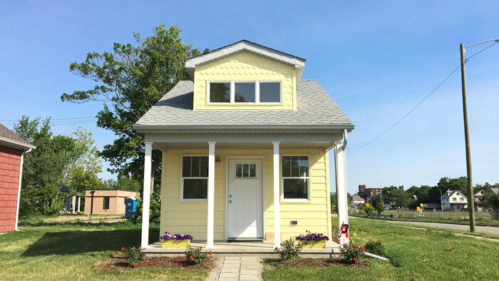 Gros plan de face d'une petite maison jaune. 
