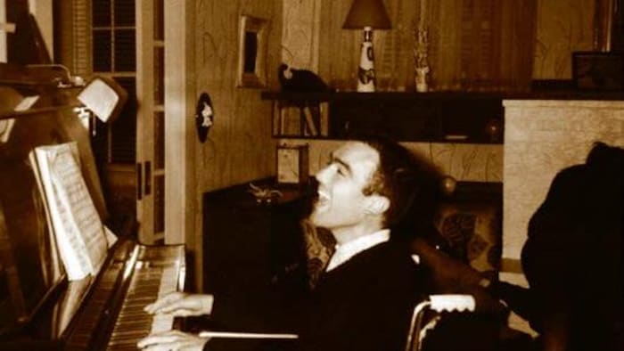 Jean-Marc, en fauteuil roulant, chante en jouant du piano.