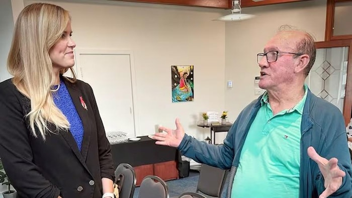 Leah Martin et Terry Paul discutent debout dans une salle de conférences en marge d'un point de presse.