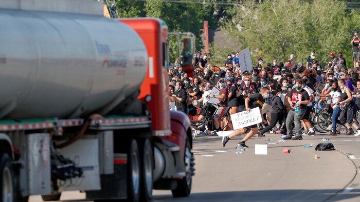 Des gens se tassent du centre de la route à l'approche du camion.