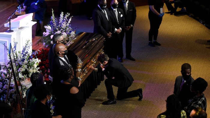 Jacob Frey agenouillé près d'un cercueil se tient le visage.