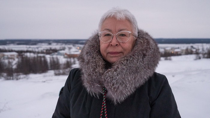 Une femme en manteau se tient devant un paysage enneigé, à Kuujjuaq, au Nunavik, en décembre 2023.