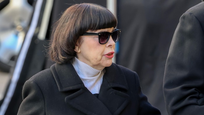 Une femme brune porte des lunettes de soleil.