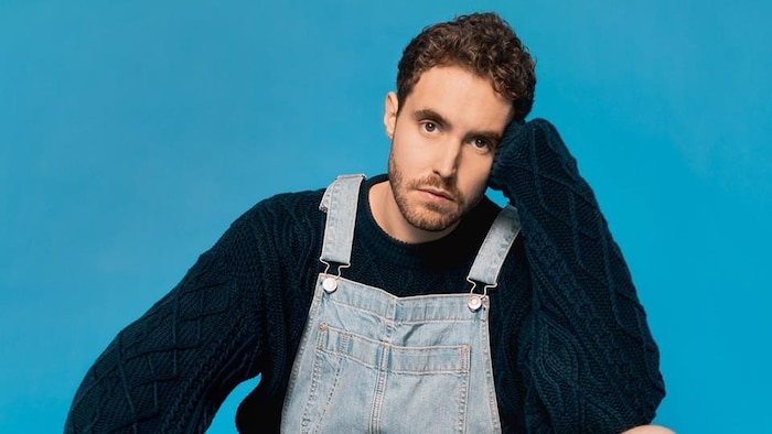 Miro wears overalls and a dark blue sweater.