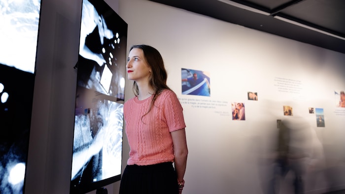 Une femme regarde des écrans dans un musée.