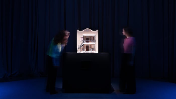 Deux femmes observent un modèle miniature d'une maison dans un musée.