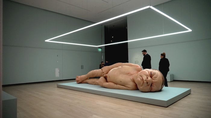 Des amateurs d'art circulent autour d'une statue hyperréaliste d'un bébé naissant mesurant 5 mètres.