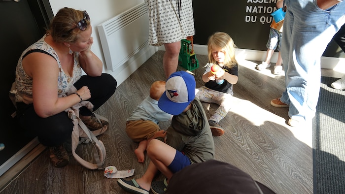 Des enfants jouent au sol, observés par une femme, dans le bureau de Catherine Blouin.