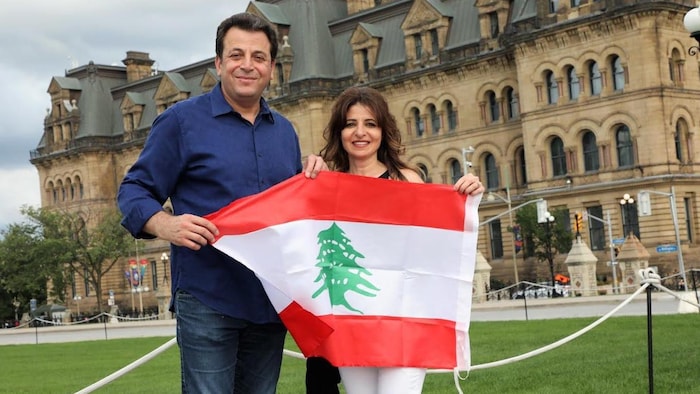اليزابيت وزياد أبو لطيف يمسكان العلم اللبناني في ساحة البرلمان في أوتاوا.