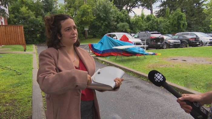 Une femme debout à l'extérieur tenant un un porte documents.