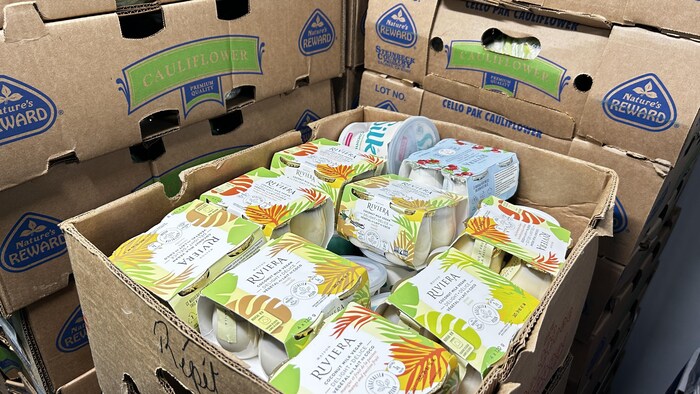 Une boîte remplie de petits pots de yogourt dans un entrepôt réfrigéré.