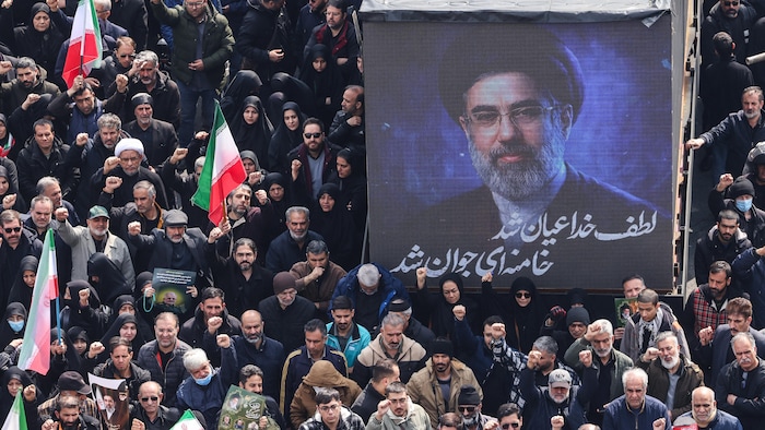 Un écran affiche le portrait du nouveau guide suprême iranien Mojtaba Khamenei lors des funérailles des commandants du Corps des gardiens de la révolution islamique et d'autres personnes tuées au cours des premiers jours des frappes américaines et israéliennes contre l'Iran, sur la place Enghelab à Téhéran, le 11 mars 2026. 