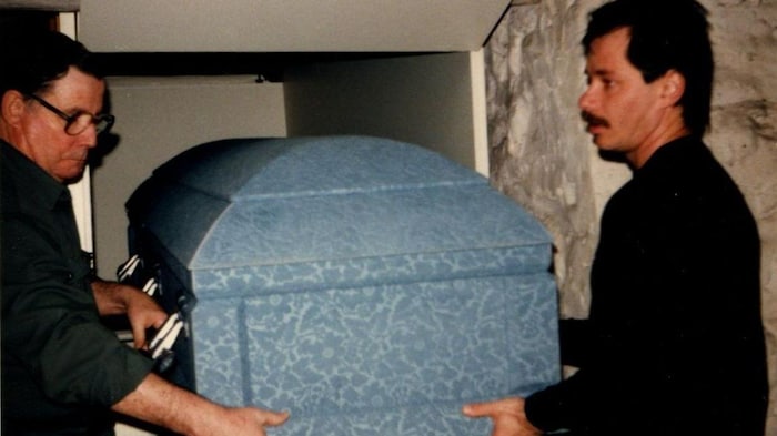Louis et Serge Boisvert placent un cercueil dans le caveau.