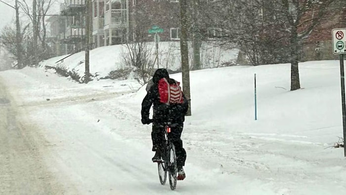 Le cycliste avance le long d'une rue un peu enneigée.