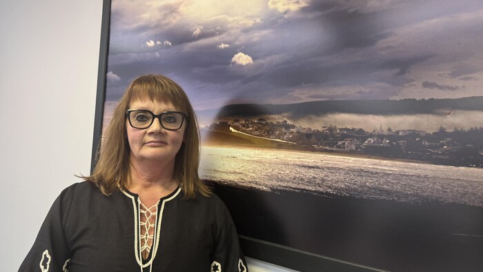 Une femme se tient devant une photo de Sainte-Anne-des-Monts.