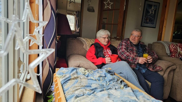 Un couple aîné assis dans un sofa de leur demeure. 