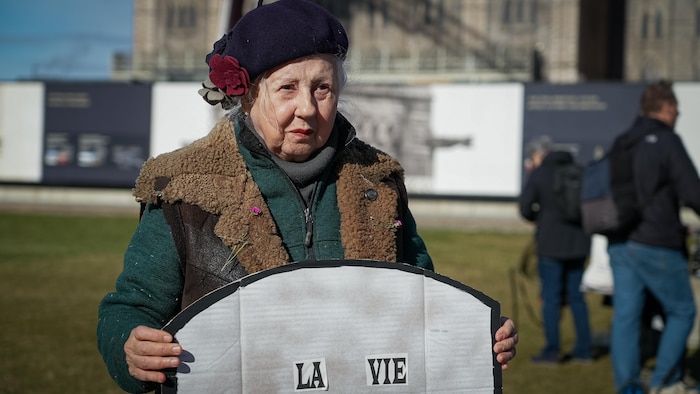 Monique Bisson tient une pancarte.