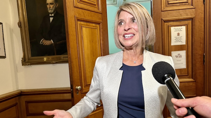 Monique Boudreau s'explique devant un micro qui lui est tendu par un journaliste.