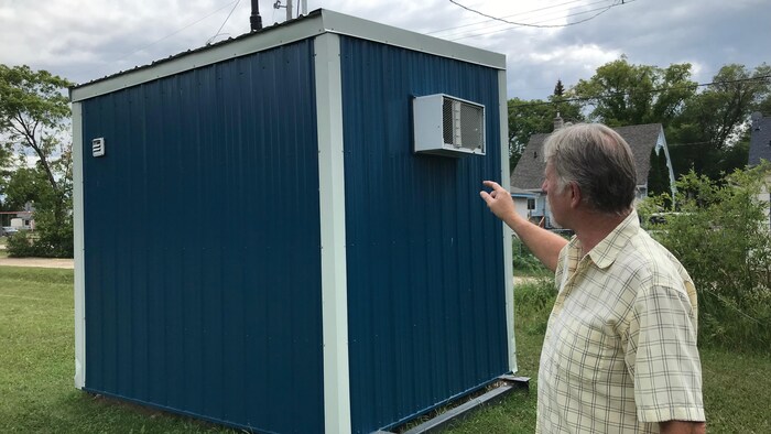 Un homme pointe du doigt une machine qui teste la qualité de l'air dans une zone résidentielle. 