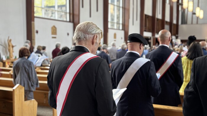 Des gens sont debout dans une église pendant une cérémonie.