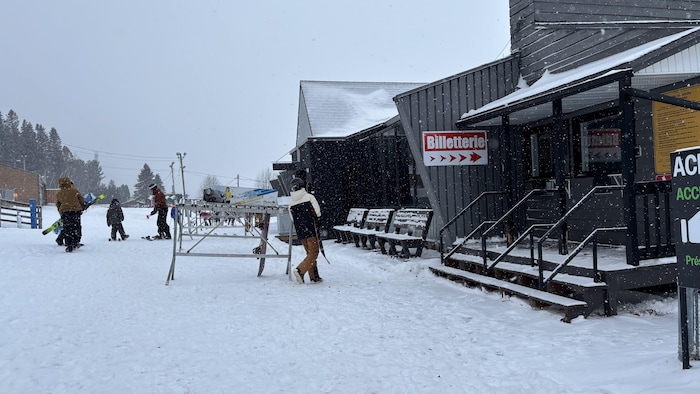 Des skieurs près du pavillon d'accueil du centre de ski. 
