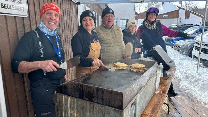 Des gens font des crêpes en extérieur. 