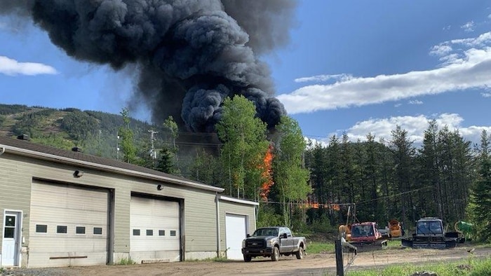 Black smoke is visible behind a garage.