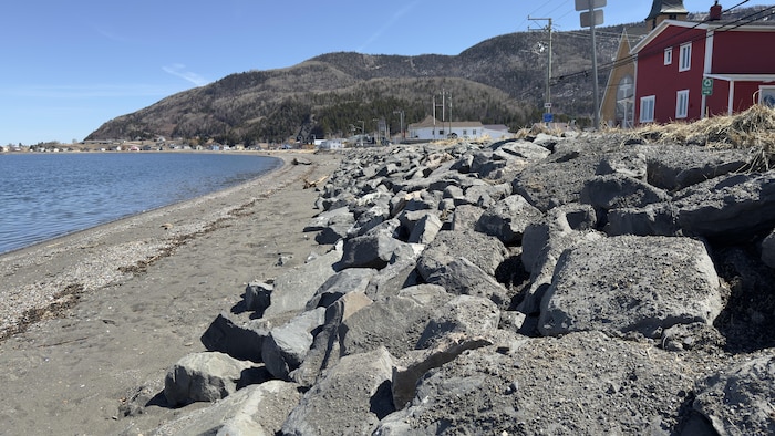 Un mur de pierre installé entre une route et une plage.