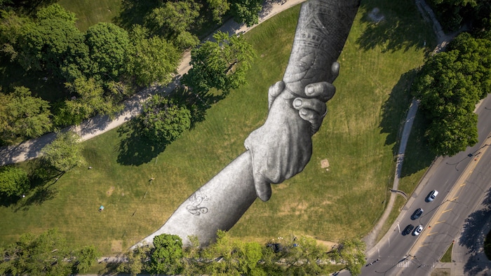 On voit deux mains qui s'entrelacent sur le gazon du mont Royal.