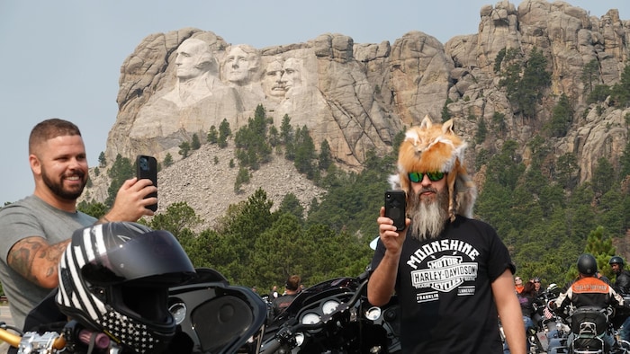 Deux motocyclistes prennent des égoportraits devant le mont Rushmore.