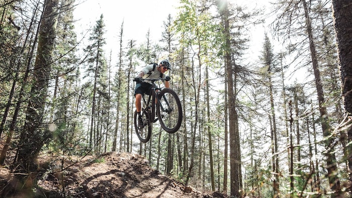Un cycliste fait un saut sur une côte dans une montagne.