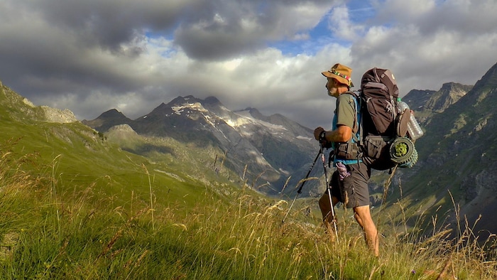 Un homme dans les montagnes portant un sac à dos.