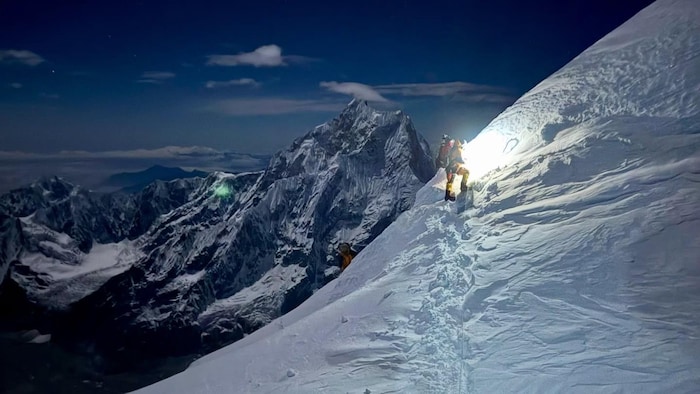 Une alpiniste monte un flanc de montagne.