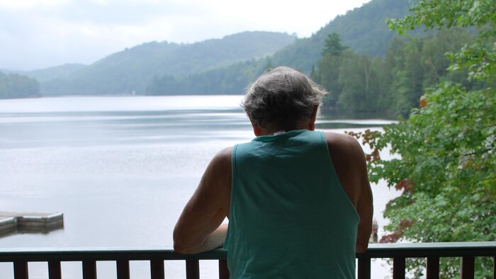 Un homme regarde un lac à partir d'un balcon.