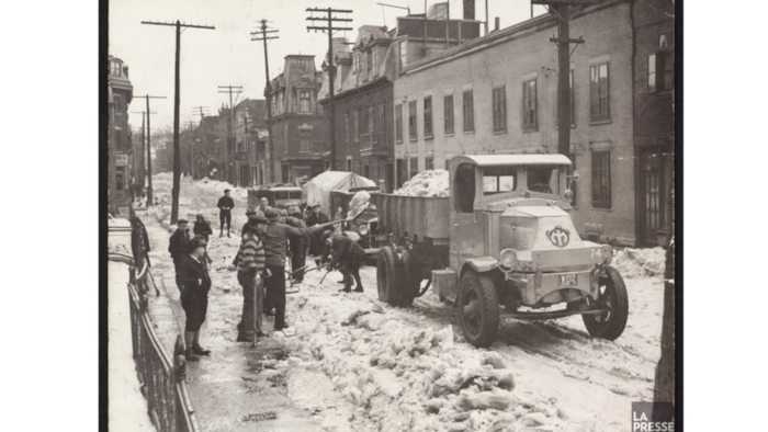 Des personnes pellettent la neige dans un camion à Montréal.