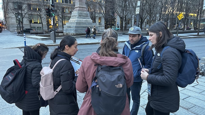 Six personnes sont rassemblées en conciliabule dans une rue du centre-ville, des questionnaires à la main.