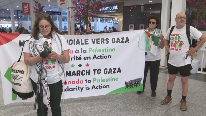 Deux femmes et un homme portant une banderole.