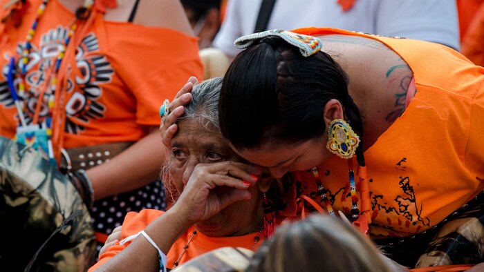 Deux personnes en pleurs qui portent un chandail orange.
