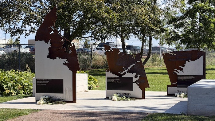 Dans un parc ensoleillé, un monument qui consiste en trois pièces de métal scuplté représentant l'Île-du-Prince-Édouard en trois morceaux et la phrase «Pas d'alcool, pas de drogues, pas de victimes».