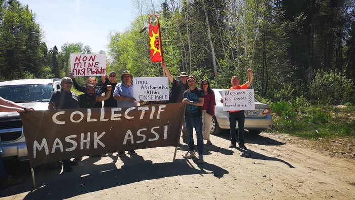 Des militants avec des banderoles bloquent un chemin forestier. 