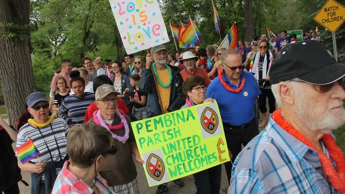 Des gens défilent avec des affiches en soutien à la communauté LGBTQ+.