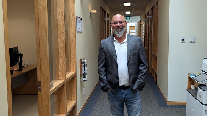 Neil Brousseau pose dans un corridor, sourire au visage et mains dans les poches.