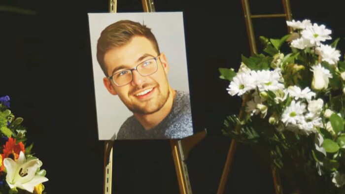 Une photo d'une personne souriante est placée au milieu des fleurs.