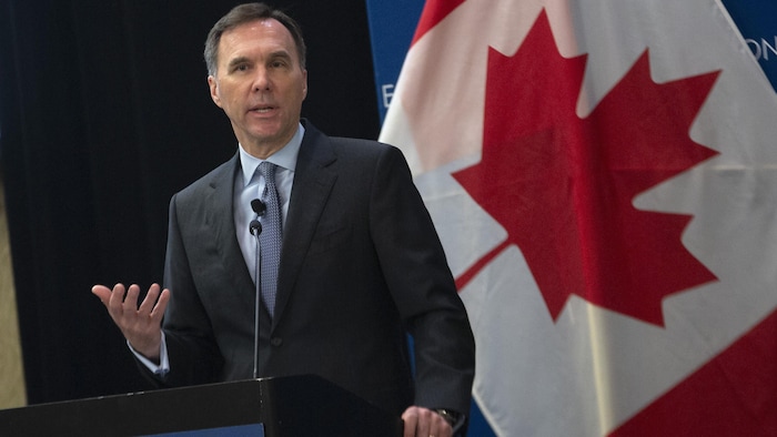 Le ministre Morneau debout devant un lutrin.