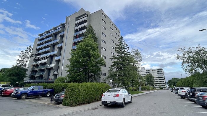 Une voiture de police est stationnée devant un immeuble de logements.